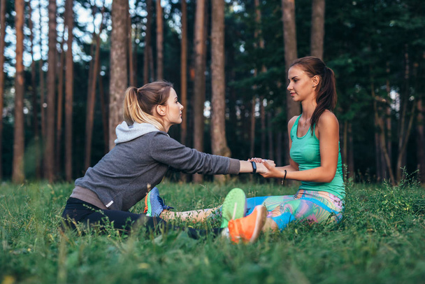Deux jolies amies pratiquant le yoga ensemble faisant une large jambe assise vers l'avant se courbent en plein air
 - Photo, image