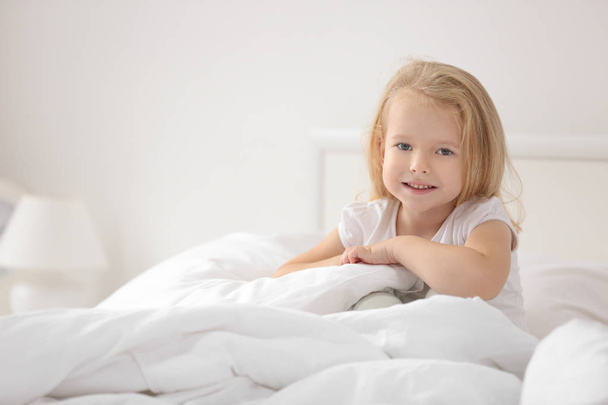 Little girl sitting on bed   - 写真・画像
