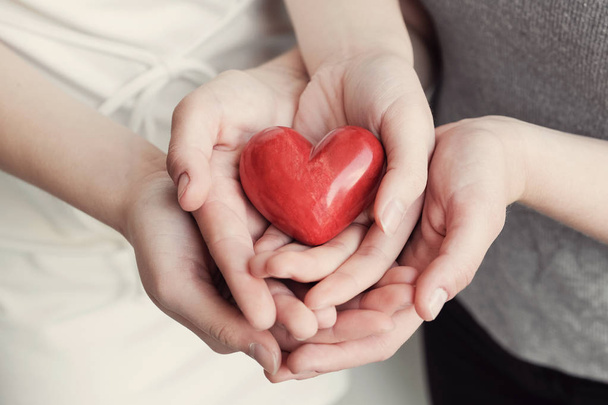 female and male hands holding red heart, health insurance, donation concept - Φωτογραφία, εικόνα