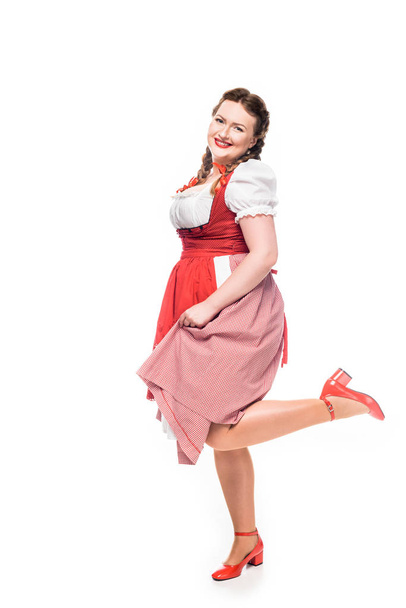 smiling oktoberfest waitress in traditional bavarian dress standing on one leg isolated on white background - Фото, зображення