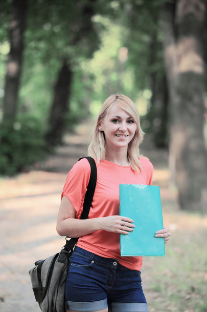 erfolgreiche Studentin mit Tasche und Klemmbrett im Hintergrund des Parks - Foto, Bild