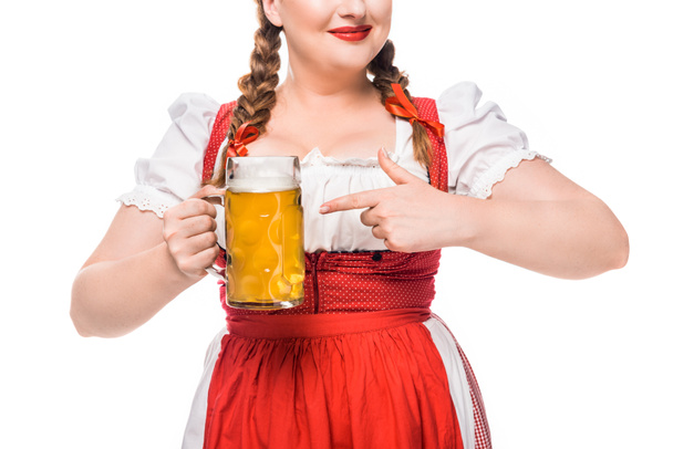 partial view of oktoberfest waitress in traditional bavarian dress pointing by finger on mug of light beer isolated on white background - Photo, Image