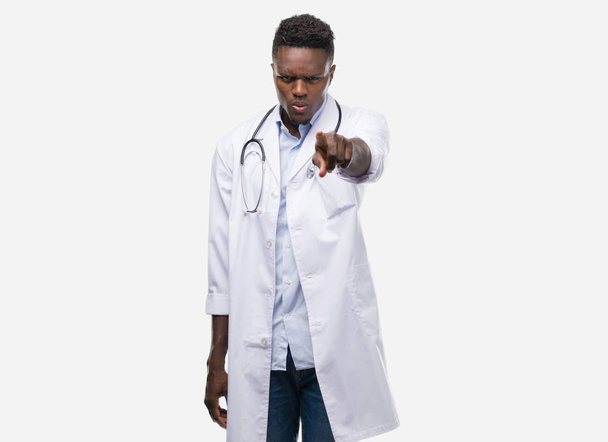 Giovane uomo afroamericano con indosso il cappotto medico che punta con il dito alla macchina fotografica e a te, segno della mano, gesto positivo e fiducioso dal davanti
 - Foto, immagini