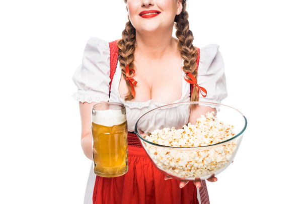 abgeschnittenes Bild einer Oktoberfestkellnerin in bayerischer Tracht mit Schüssel mit Popcorn und einem Becher hellem Bier auf weißem Hintergrund - Foto, Bild