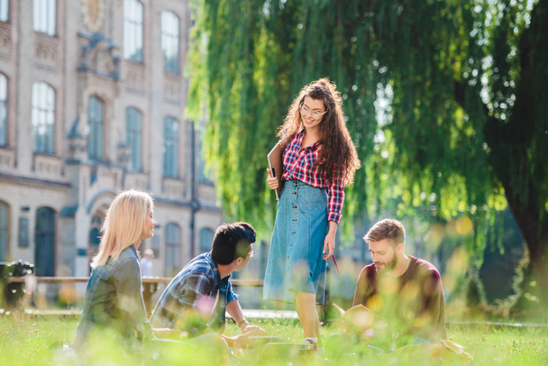 multiracial students resting in park with university on background - Photo, image