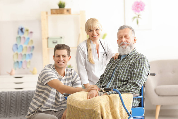 Caregiver with senior man and his son at home - Foto, Imagen