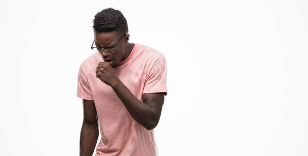 体調不良や風邪や気管支炎の症状として咳を感じてピンクの t シャツを着て若いアフリカ系アメリカ人。ヘルスケアの概念. - 写真・画像