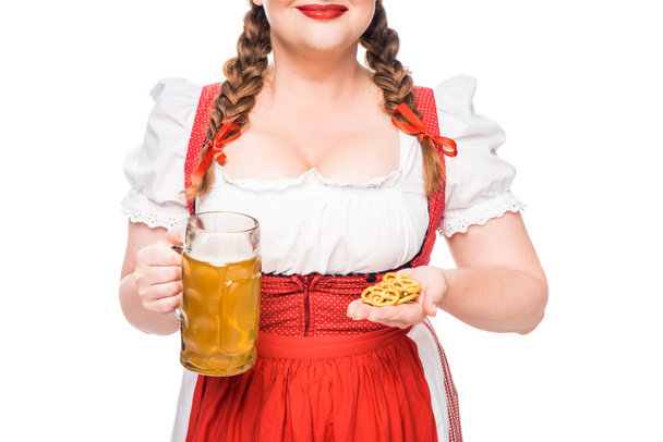 cropped image of oktoberfest waitress in traditional bavarian dress showing little pretzels and mug of light beer isolated on white background - Fotografie, Obrázek