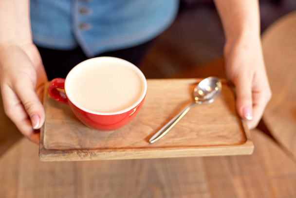 Close view of woman holding wooden tray with aroma cup of coffee - Photo, Image