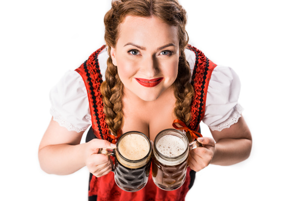 high angle view of oktoberfest waitress in traditional bavarian dress holding mugs with light and dark beer isolated on white background - Photo, Image