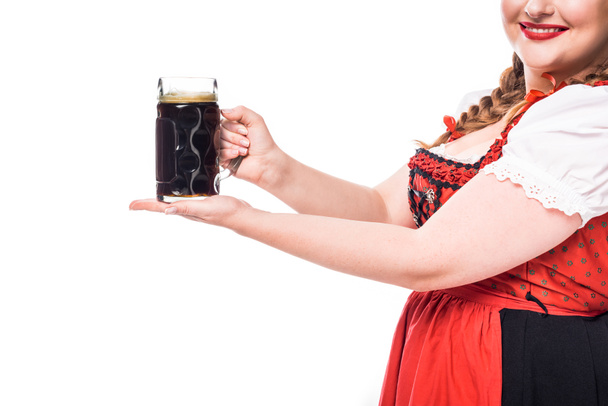 cropped image of oktoberfest waitress in traditional bavarian dress holding mug of dark beer isolated on white background - Photo, Image