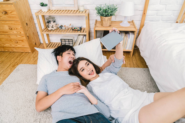 Vista dall'alto di Happy Asian Lover utilizzando la tecnologia smart phone per selfie sul pavimento con tappeto in camera da letto a casa, concetto di selfie coppia
, - Foto, immagini