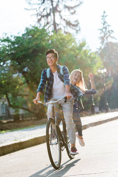 happy multiethnic students riding bicycle together on street - Foto, Imagen