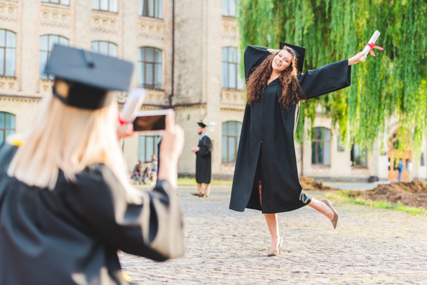 vista parziale della donna che scatta foto di compagno di classe con diploma durante la laurea presso l'università
 - Foto, immagini