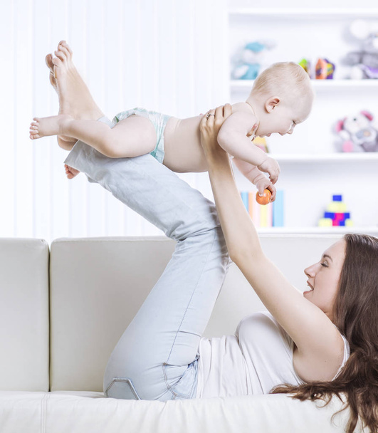 concept of happiness:happy mother playing with one year old baby in the room for children - Fotó, kép