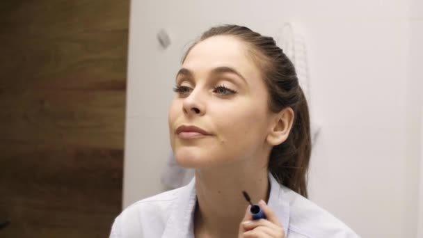 Woman applying mascara on her lashes in bathroom - Imágenes, Vídeo