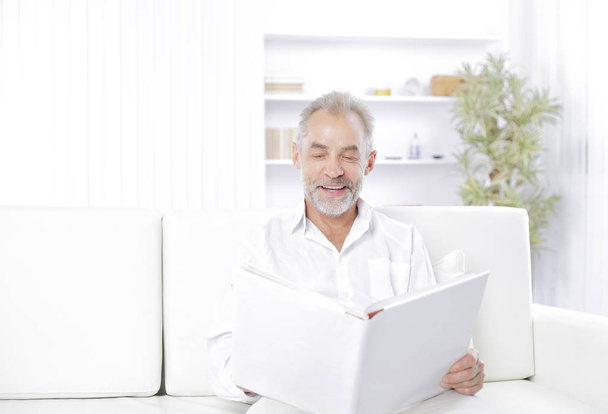 Smiling senior man reading file folder on the couch - Φωτογραφία, εικόνα