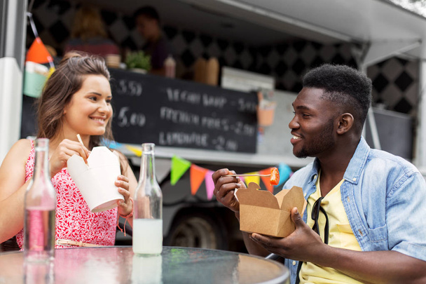 mixed race couple eating and talking at food truck - Fotoğraf, Görsel