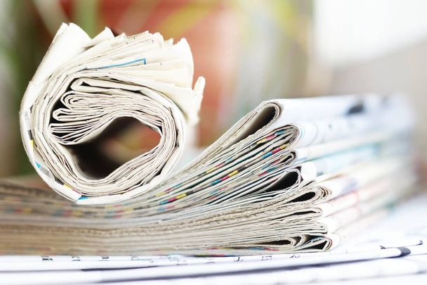 圧延と 2 つ折りの新聞は机の上に山に積まれて。タブロイド紙の見出しや記事をオフィスのテーブルの上。コミュニケーションおよび情報のためのコンセプト   - 写真・画像