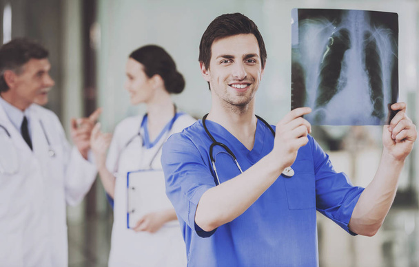 X-ray Scan glimlachend chirurg zorgvuldig onderzoeken. - Foto, afbeelding