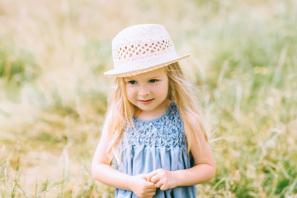 adorable blonde child in dress and straw hat - Fotó, kép