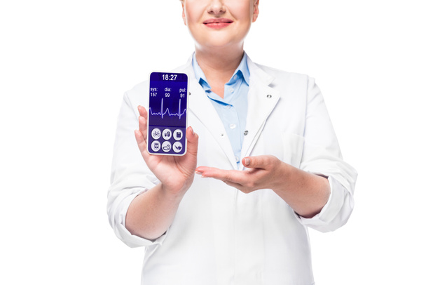 περικομμένη εικόνα γυναίκα γιατρό δείχνοντας smartphone με οθόνη καρδιακός ρυθμός οθόνη που απομονώνονται σε λευκό φόντο  - Φωτογραφία, εικόνα