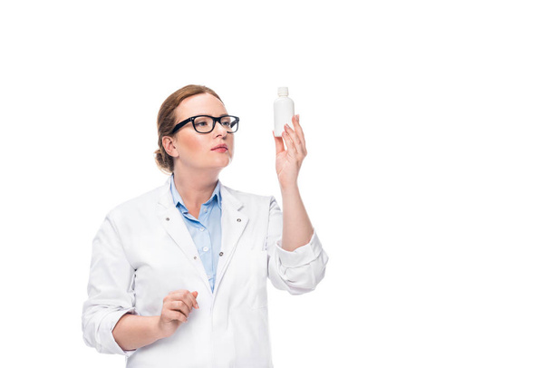 female doctor in eyeglasses looking at pill bottle isolated on white background  - Fotoğraf, Görsel