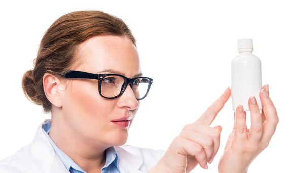 ernsthafte Ärztin mit Brille zeigt mit dem Finger auf Tablettenflasche isoliert auf weißem Hintergrund  - Foto, Bild