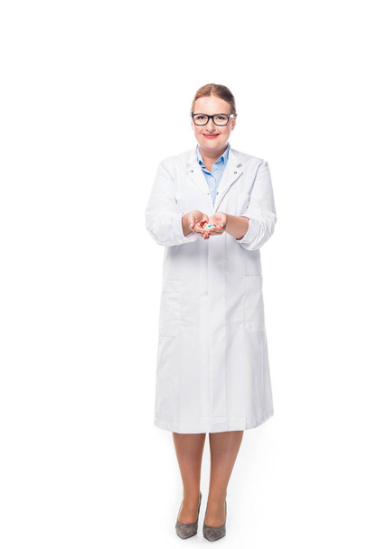 smiling female doctor in eyeglasses showing pills isolated on white background - Fotografie, Obrázek