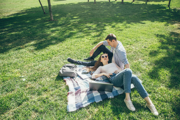 Young couple in love resting on the lawn after school on a Sunny day. - Φωτογραφία, εικόνα