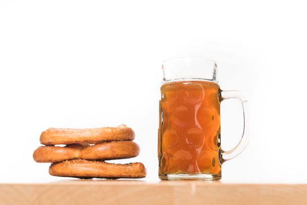 selective focus of pretzels and mug of beer on wooden table on white background  - Foto, Imagem