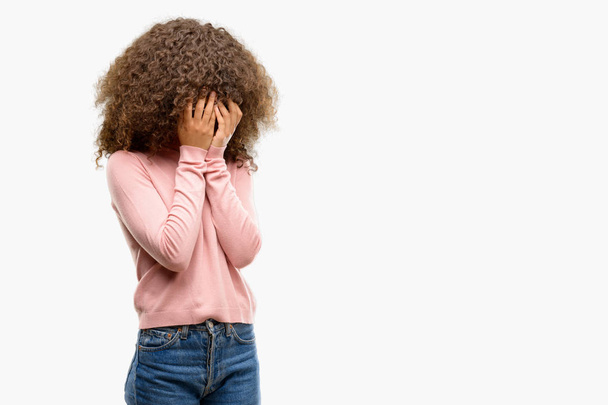 Femme afro-américaine portant des lunettes de soleil roses avec une expression triste couvrant le visage avec les mains tout en pleurant. Concept de dépression
. - Photo, image