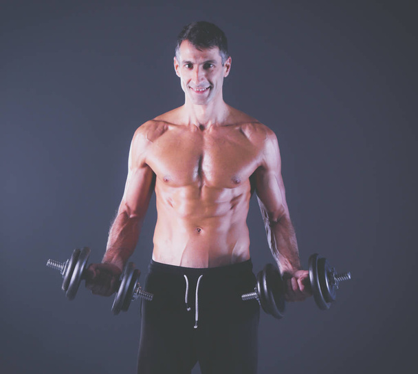 Handsome muscular man working out with dumbbells. Personal fitness instructor. Personal training. - Φωτογραφία, εικόνα