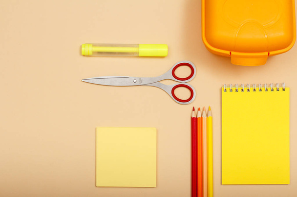Note paper, felt pen, scissors, color pencils, lunch box and notebook on beige background. Top view. Back to school concept. School supplies - Foto, Bild