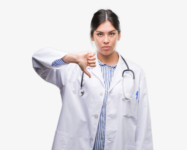 Fiatal latin doktor nő, haragos arc, negatív előjellel mutatja ellenszenv a hüvelykujját lefelé elutasítás koncepció - Fotó, kép