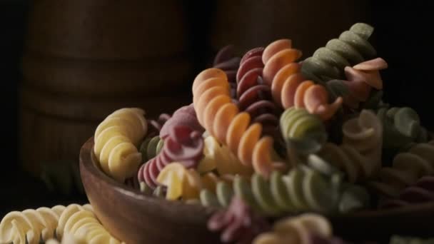 Sušené těstoviny fusilli barevné na dřevěné desce - Záběry, video