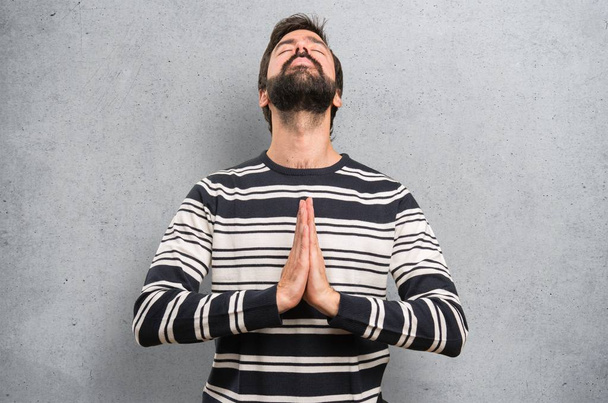 Homem com barba em posição zen sobre fundo texturizado
 - Foto, Imagem