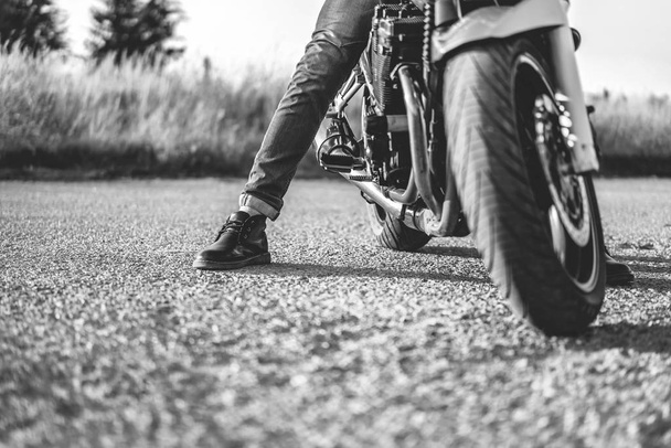 Biker sitting on sport motorcycle and putting leg on asphalt road, close-up  - Fotoğraf, Görsel