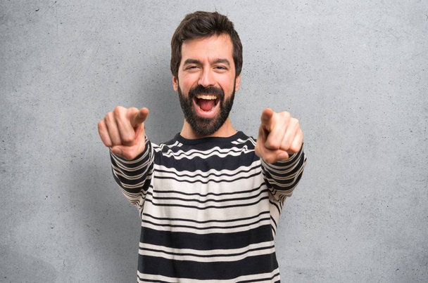 Man with beard pointing to the front on textured background - Photo, Image