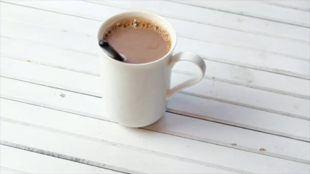 Chocolate caliente en una taza blanca sobre fondo de madera
 - Metraje, vídeo