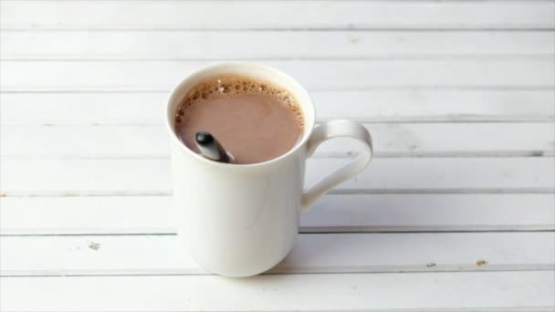 Chocolate caliente en una taza blanca sobre fondo de madera
 - Metraje, vídeo