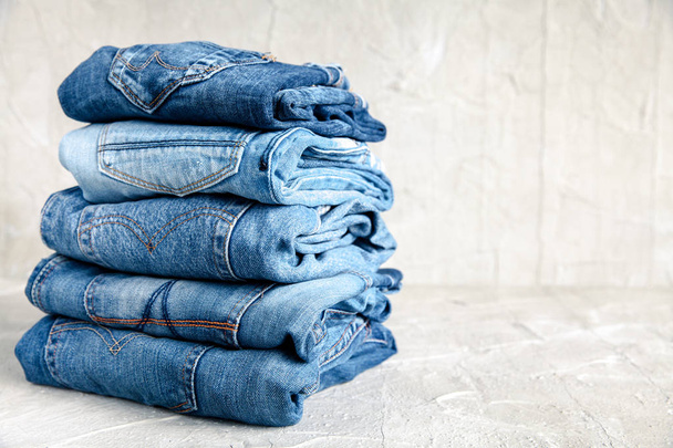 stack of blue jeans on a gray background - Foto, Imagem