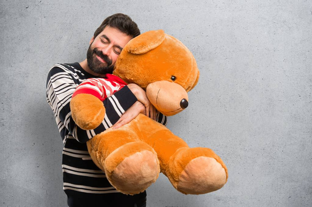 Счастливый человек с бородой играет с фаршированным животным на фактурном фоне
 - Фото, изображение