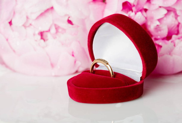 red velvet box with wedding ring against peony flowers - Fotoğraf, Görsel