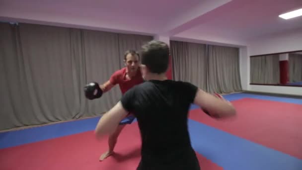 Young kickboxing fighter hitting pads with his coach in gym - Video