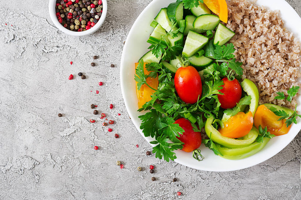 Diet menu. Healthy vegetarian salad of fresh vegetables - tomatoes, cucumber, sweet peppers and porridge on bowl. Vegan food. Flat lay. Top view - Photo, Image