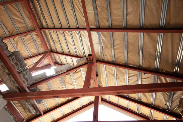 Сталева рама з ізоляційним листом під дахом будинку на будівельному майданчику
  - Фото, зображення
