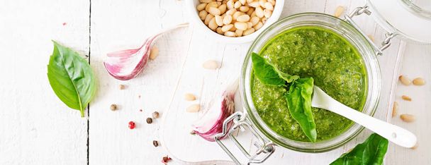Homemade pesto sauce fresh basil, pine nuts and garlic on white wooden background. Italian food. Top view with copy space - Fotografie, Obrázek