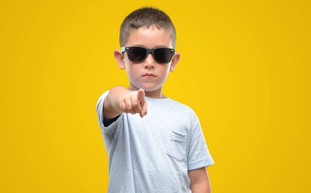 Niño de cabello oscuro con gafas de sol apuntando con el dedo a la cámara y a ti, signo de mano, gesto positivo y seguro desde el frente
 - Foto, Imagen