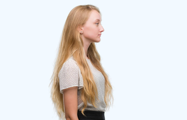 Blonde teenager woman wearing moles shirt looking to side, relax profile pose with natural face with confident smile. - Photo, Image